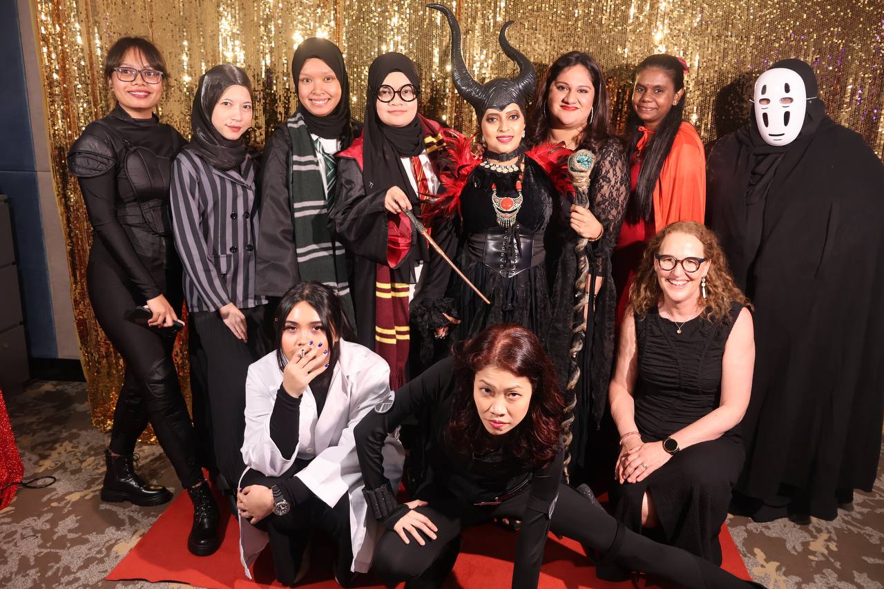 A team celebrating together in front of the photobooth backdrop at a company event